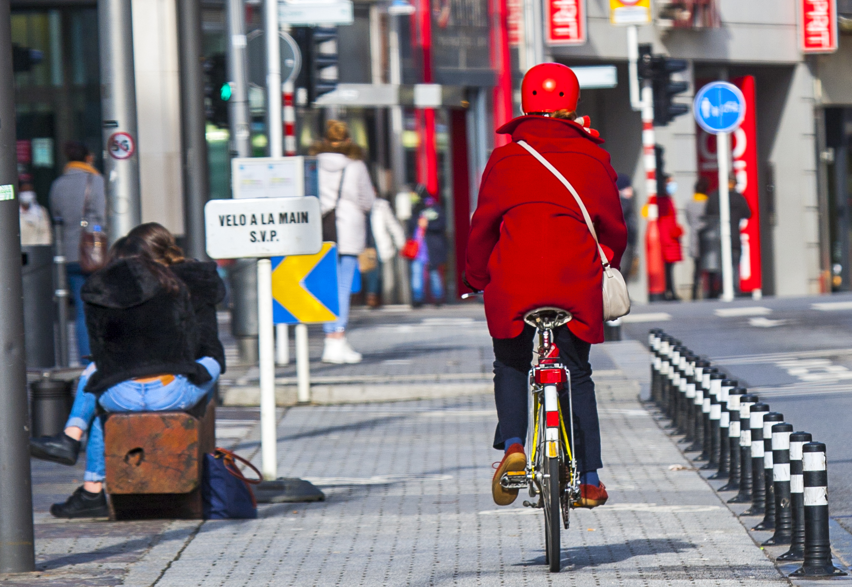 mujer en bicicleta con chaqueta roja en la ciudad de Luxemburgo en las cercanías de la gare centrale donde conecta con el resto del país